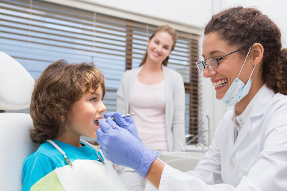 A dentist checking a boy's teeth with Kapolei dental.